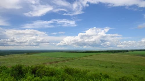 Zeitraffer wunderschöner weißer Wolken, die über den blauen Himmel über grünen Hügeln schweben