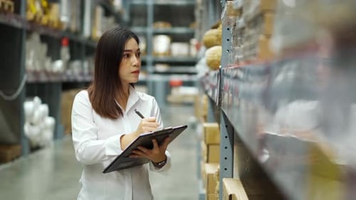 junge Arbeiterin hält Zwischenablage in der Hand und überprüft Inventar im Lagerhaus