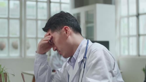 Stressed Doctor Rubbing Forehead in Medical Workplace