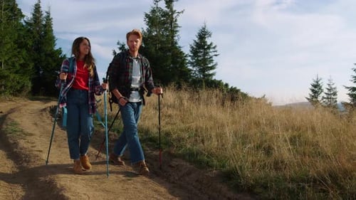 Couple Hiking With Trekking Poles in Mountains