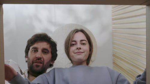 Couple Excitedly Looks Into an Open Cardboard Box