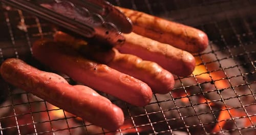 Sausages Grilling Over Open Flame at Night