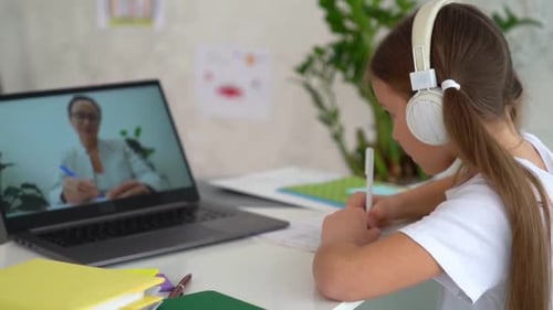 Girl Attends Online Class and Writes in Notebook
