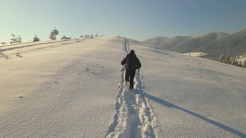 Aerial View of Backpacker Hiking Snowy Mountain Hillside on Cold Winter Morning