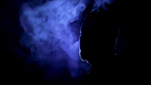 Silhouette of Man Exhaling Vapor With Blue Light