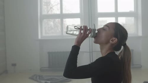 Woman Drinking Water After Workout Indoors