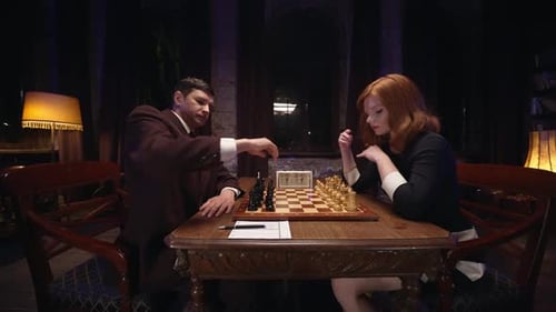 Man and Woman Play Chess Indoors at Night