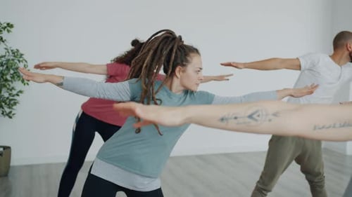 Slow Motion of Group of Young People Training with Instructor in Yoga Studio