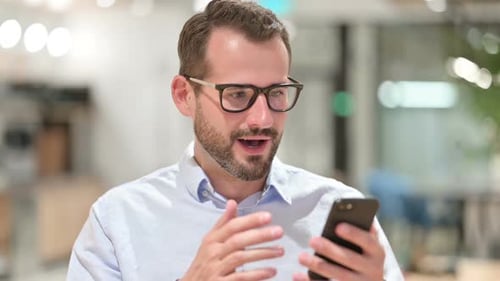 Excited Man Celebrating Success on Smartphone