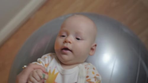 Baby Lying on Exercise Ball, held by Adult