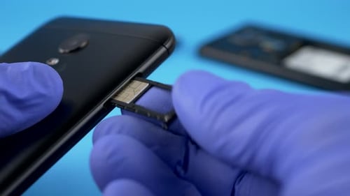 Gloved Hand Inserting SIM Card Into Smartphone