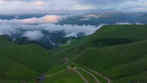 Drone Flight above green fields at the mountains in the clouds and fog