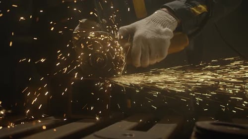 Industrial worker using an angle grinder and cutting a metal square pipe