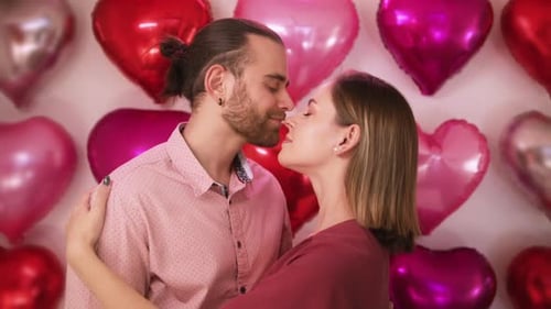 Loving Couple Embrace in Front of Heart Balloons