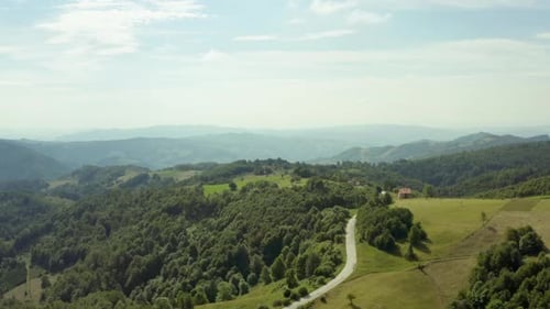 Vista aérea sobre el camino que serpentea entre campos verdes con árboles