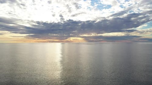 AERIAL: Flying Very Slowly Backwards Baltic Sea During Golden Hour with Blue and Orange Sky