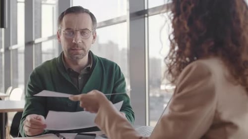 Man and Woman Discussing Finance Documents in Office