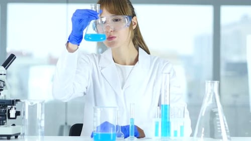 Scientist Examining Blue Liquid in Lab Beaker