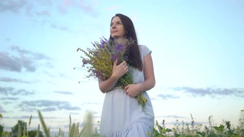 Young Woman Walking With Bouquet of Field Flowers