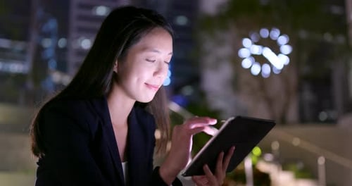 Woman Using Tablet at Night in City