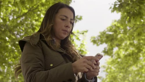 Young Woman Using Cell Phone in City Park