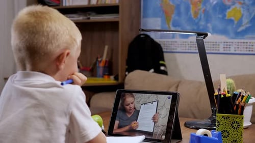 Boy Watches Teacher on Tablet for Online School