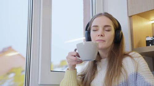 Woman Listening to Music Enjoying Drink By Window