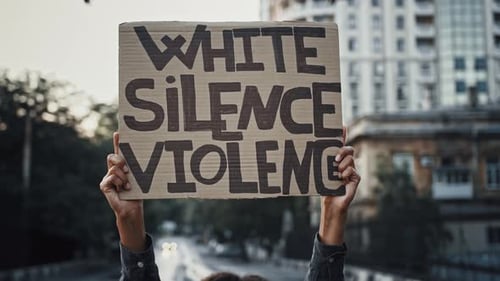 Person Holding Protest Sign in Urban Setting