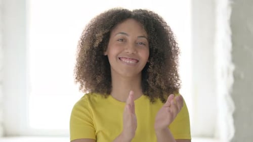 Woman Smiling and Clapping in Bright Indoor Setting