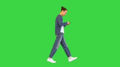 Young White Man Walks Typing Something on His Smartphone on a Green Screen Chroma Key