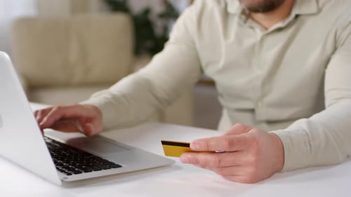 Man Using Laptop with Credit Card Indoors