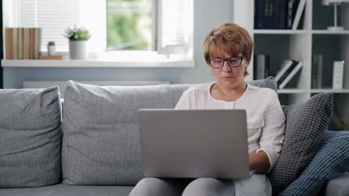 Woman Using Laptop on Couch in Living Room