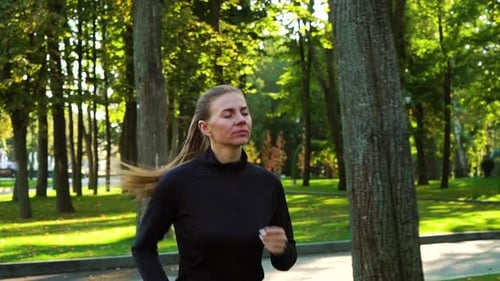 Young Woman Running in Sunlit Park