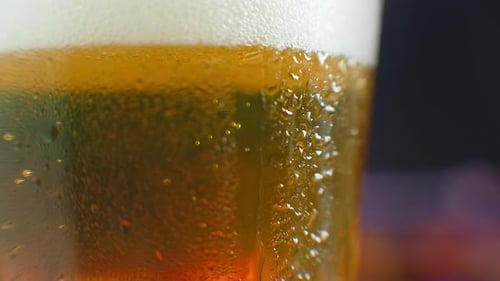 Makroaufnahme eines Tropfens, der über ein Glas Bier läuft. Bei einem kalten Glas Bier schwitzen. Ein tropfender Tropfen auf