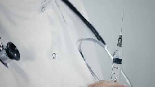 Nahaufnahme von Flüssigkeitsstreuseln aus der Nadel der Spritze