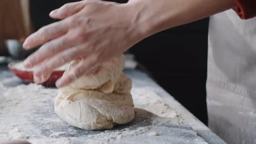 Hands Kneading Dough on a Floured Surface