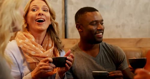 Group of happy friends interacting while having coffee in the restaurant 4K 4k