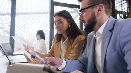 Collaborative Young Professionals Reviewing Documents in Modern Workplace