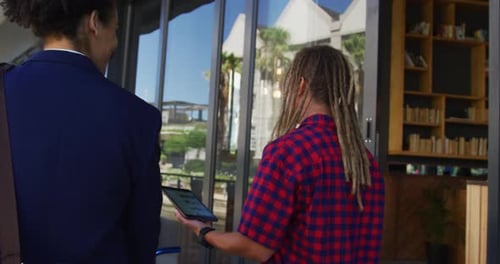 Two diverse male friends walking in the street using a digital tablet