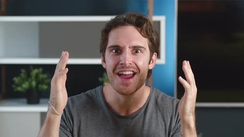 Excited young man reacts with surprise indoors