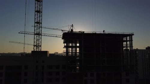 Construction Site at Sunset. Silhouette of a Construction Crane Near the Building