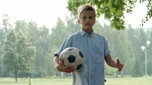 Boy Holding Soccer Ball in a Green Park