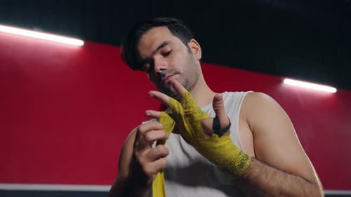4K Caucasian man wrapping hands with boxing wraps while do boxing exercise at gym.