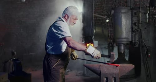Senior Blacksmith Working on Metal at Forge