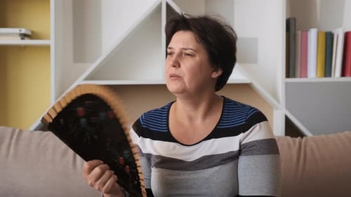 Woman Cooling Herself with a Handheld Fan at Home
