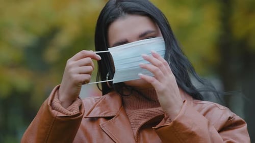 Young Woman Puts on Surgical Face Mask