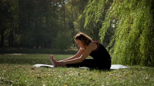 Woman Stretches on Yoga Mat in Urban Park