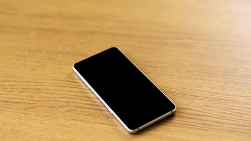 Smartphone with Blank Black Screen on Wooden Table