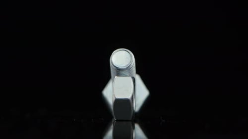 Bolt and Screw Rotate on Glass Black Stand in Closeup