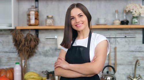 Smiling Woman Standing in Kitchen with Arms Crossed